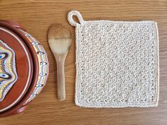 a crocheted pot holder and wooden spoon rest on top of a wood table