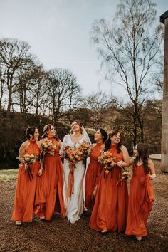 a group of women standing next to each other wearing orange dresses and holding bouquets