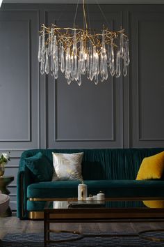 a living room with a green couch and chandelier hanging from the ceiling above it