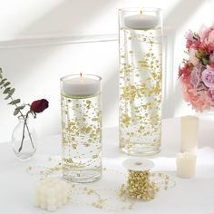 two vases with candles and flowers on a table