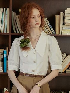 a woman standing in front of a bookshelf with her hands on her hips