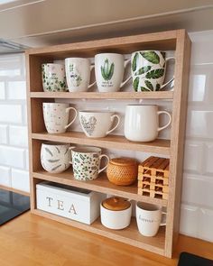 a wooden shelf filled with cups and mugs