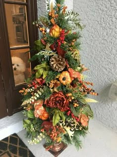 a christmas tree is decorated with orange and green flowers, pine cones, berries and leaves