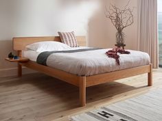 a bed sitting on top of a wooden floor next to a brown chair and window