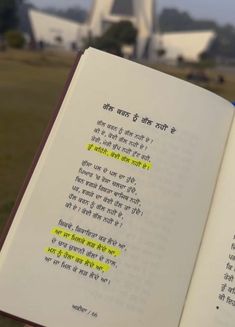 an open book with some writing on it in front of a building and trees,