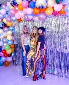 three women standing in front of balloons and streamers