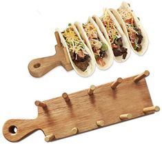 three tacos are on a cutting board and one is being held by a knife