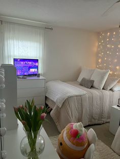 a bed room with a neatly made bed next to a desk and tv on top of it