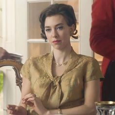 a woman sitting at a table in front of a mirror with her hands clasped to her chest