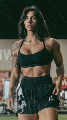 a woman standing on top of a soccer field wearing black shorts and a sports bra