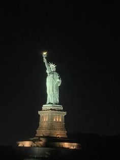 the statue of liberty is lit up at night with its lights on and it appears to be glowing