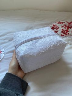 a person is laying on a bed with a white bag in front of them and two red pillows next to it