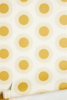 a yellow and white wallpaper with sunbursts on the side, next to a bed