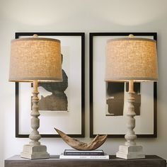 two lamps sitting on top of a wooden table next to a framed photo and book