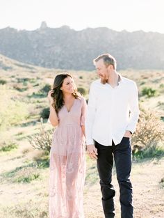 a man and woman walking in the desert holding hands