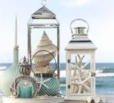 two white lanterns sitting on top of a sandy beach