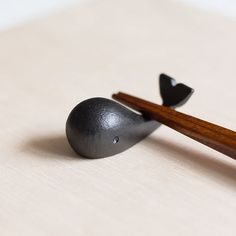 two chopsticks sticking out of the side of a black object on a white surface