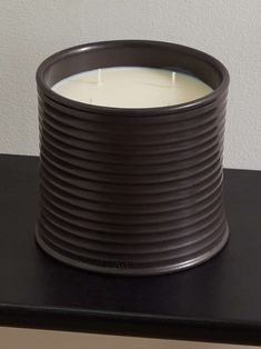 a candle sitting on top of a table next to a white wall and black counter