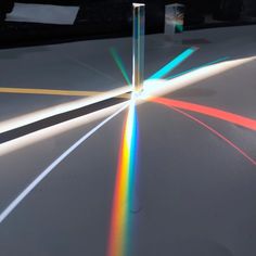 an object is shown with light coming from it's center and rainbow colored beams on the floor