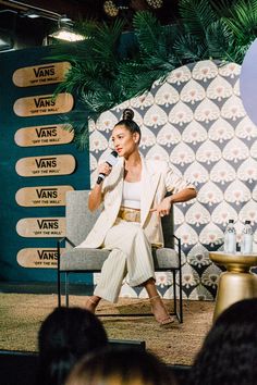 a woman sitting in a chair while holding a microphone