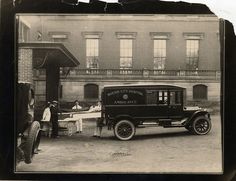 an old black and white photo of people in front of a building with a truck