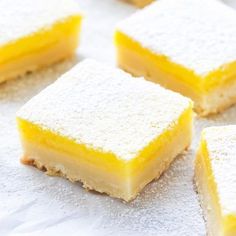 several pieces of yellow cake sitting on top of a white tablecloth covered in powdered sugar