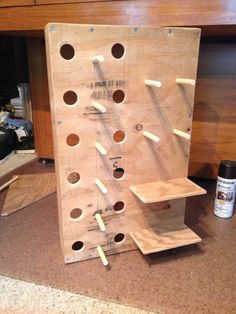 a wooden peg board with holes in it on the floor next to a table and some other items