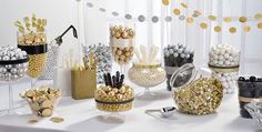 a table topped with lots of different types of candies and candy bar containers filled with gold and silver confetti