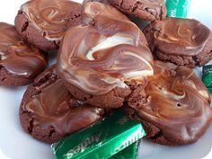 chocolate cookies with marshmallows are on a plate next to green candy bars