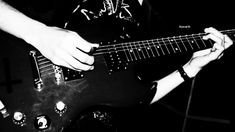 black and white photograph of a person playing an electric guitar with their hands on the strings