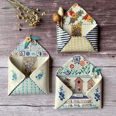 two small envelopes sitting next to each other on top of a wooden table with flowers