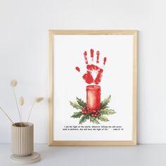 a red hand print on a white wall next to a vase with flowers in it