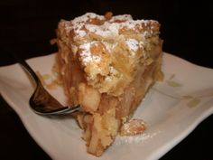 a piece of cake with powdered sugar on top and a fork in the foreground