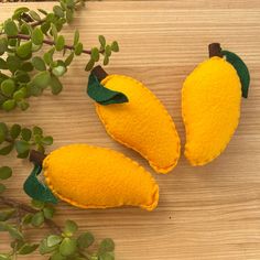 three pieces of yellow fruit sitting on top of a wooden table next to green leaves