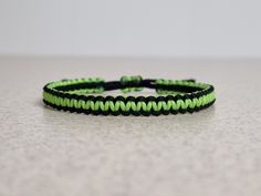 a green and black paracorine bracelet sitting on top of a white countertop