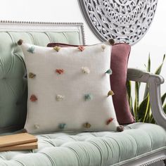 a couch with two pillows on it and a book in front of the pillow cover