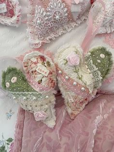 two heart shaped stuffed animals are laying on a pink and white lace covered bed sheet