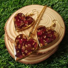 three heart shaped pendants sitting on top of a piece of wood in the grass