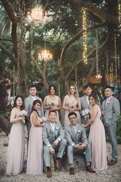 a group of people standing next to each other in front of a tree with lights