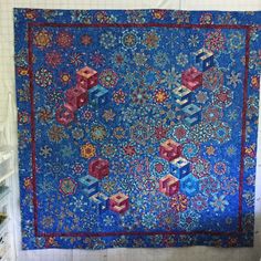 a blue and red quilt hanging on the wall