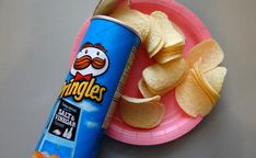 a pink plate topped with chips next to a can of pringle's