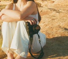 a woman sitting on top of a rock with a camera