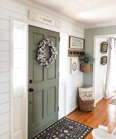 a green door with a wreath on it and some baskets hanging from the wall next to it