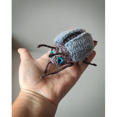 a hand holding a tiny crocheted spider with blue eyes