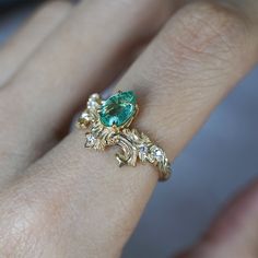 a close up of a person's hand with a green ring on their finger