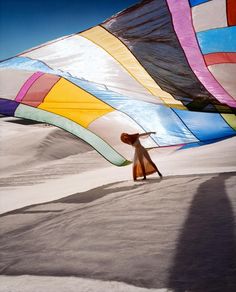 a person standing under a large colorful kite