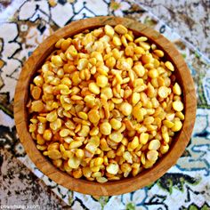 a wooden bowl filled with corn on top of a rug