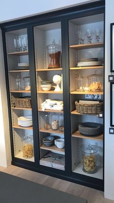 an open glass door cabinet with dishes and bowls in the bottom shelf, on display