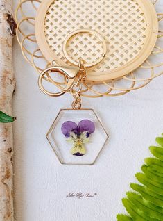 a purple pansyflower in a glass hexagonal pendant on a gold chain