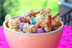 a bowl filled with cereal and candy on top of a pink table cloth next to a window